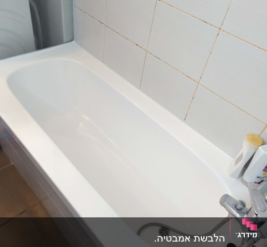 אמבטיה לבנה עם ברז מתכת וקיר אריחים לבנים
